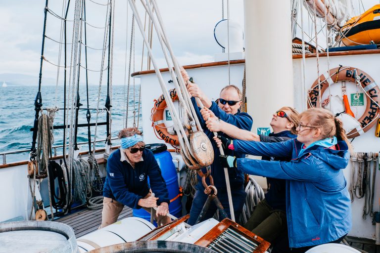 BLue Clipper guests raising sails pulling ropes 768x512