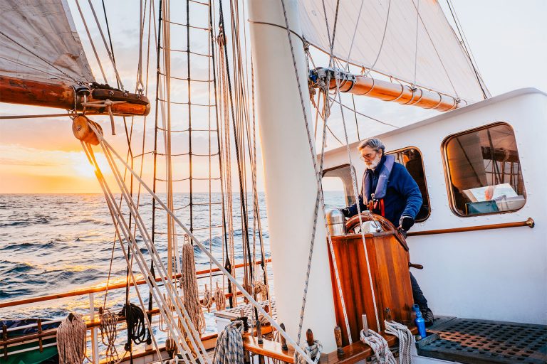 Blue Clipper guest at helm at sunset tall ship 768x512